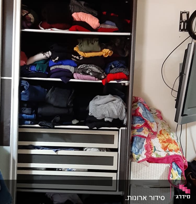 ארון בגדים עם מדפים מלאים בבגדים מקופלים